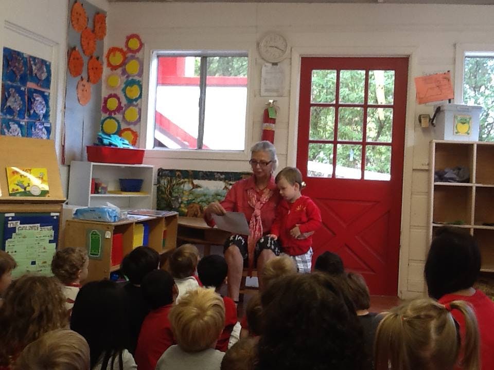 Person reading to a child on lap and other children in a classroom