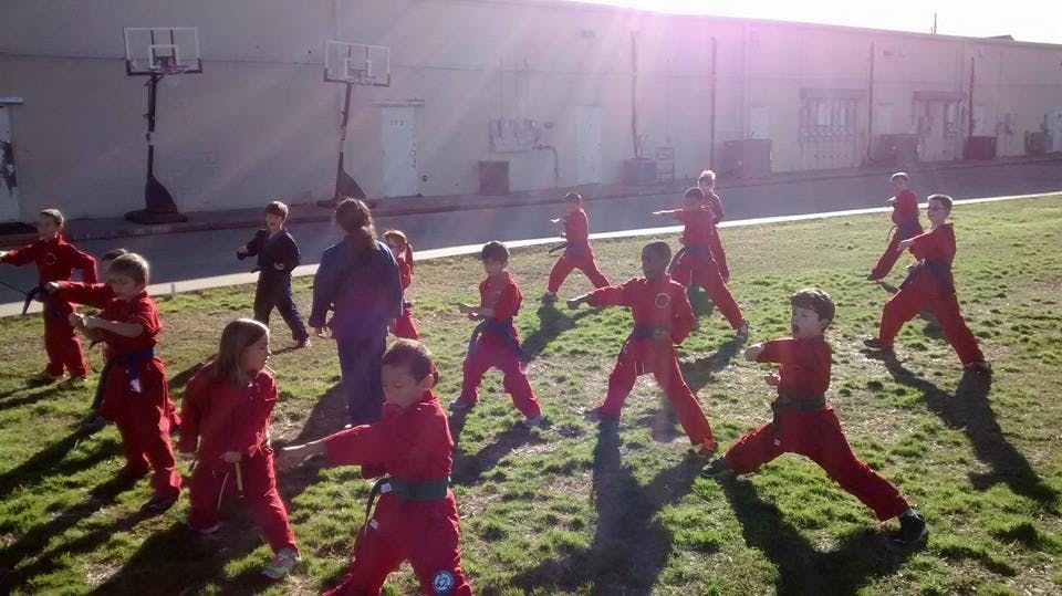 Children in red uniforms practicing martial arts outdoors
