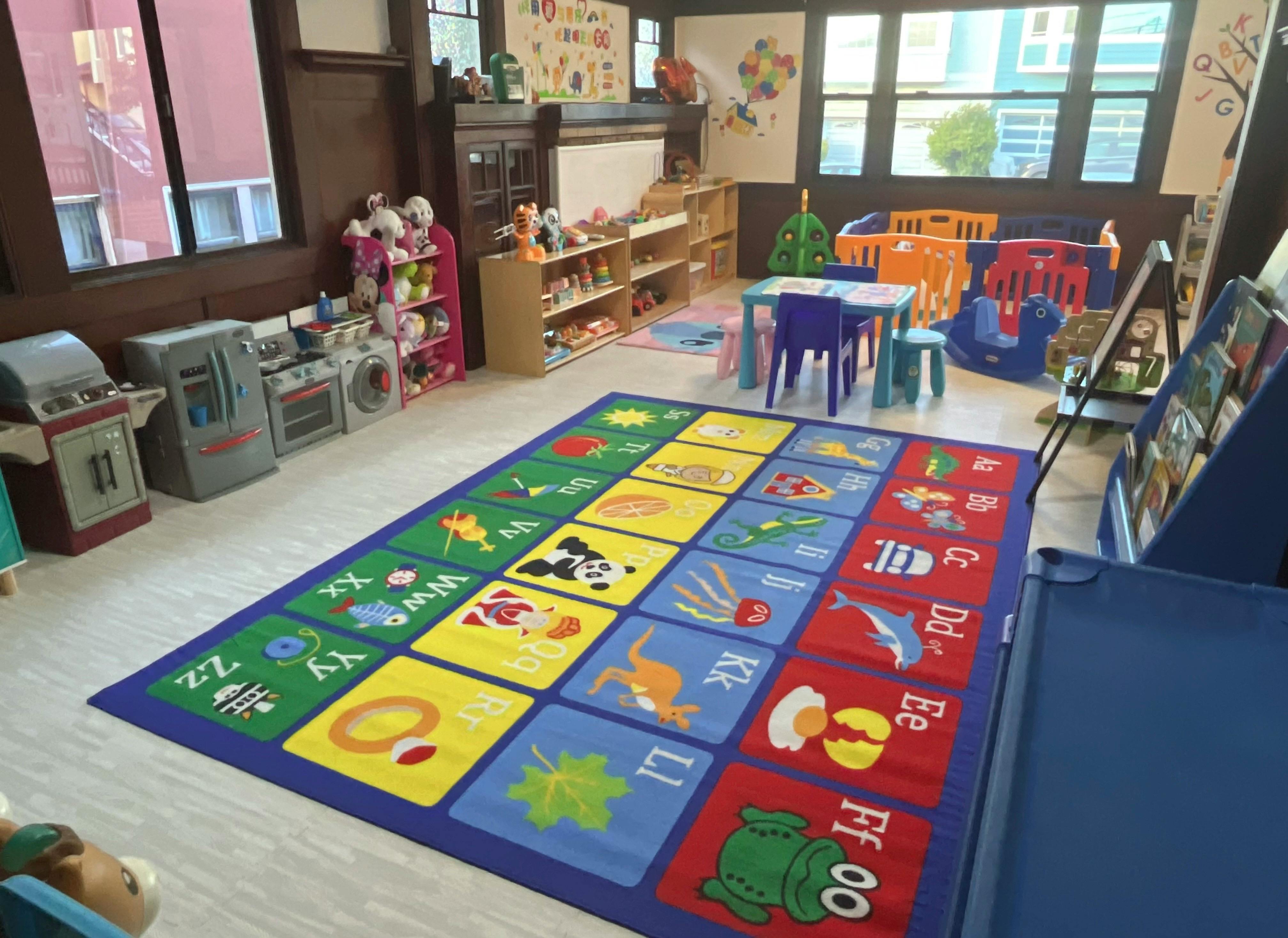Playroom with an alphabet rug, small tables, and toy kitchen appliances