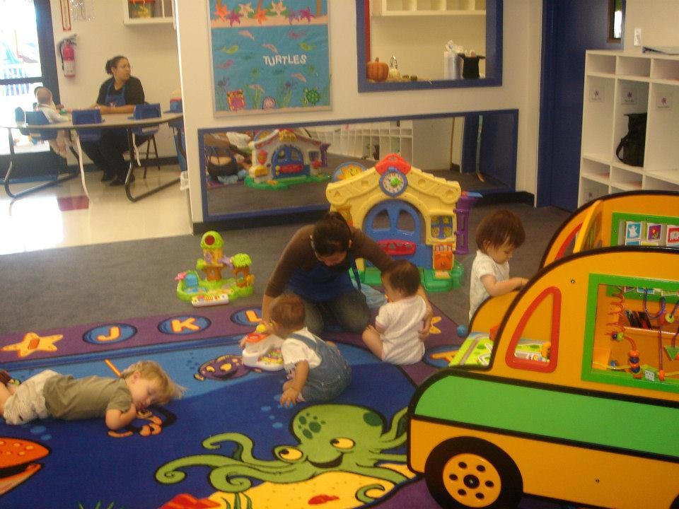 Adult and children playing on a colorful rug in a room