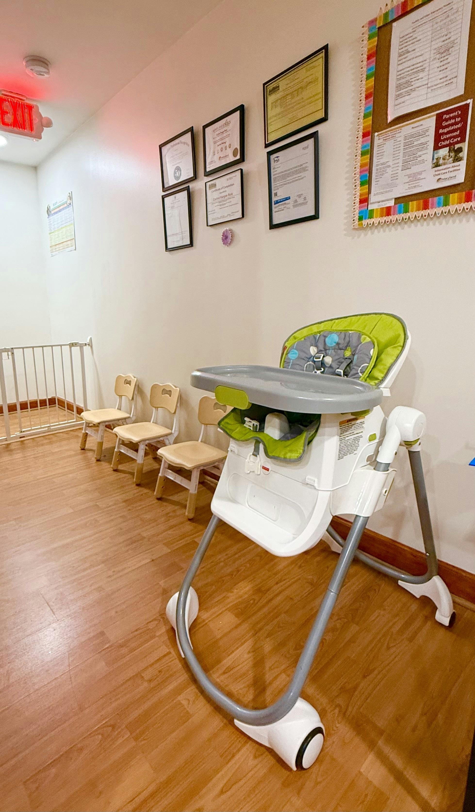 High chair in a child care facility with small chairs and wall certificates