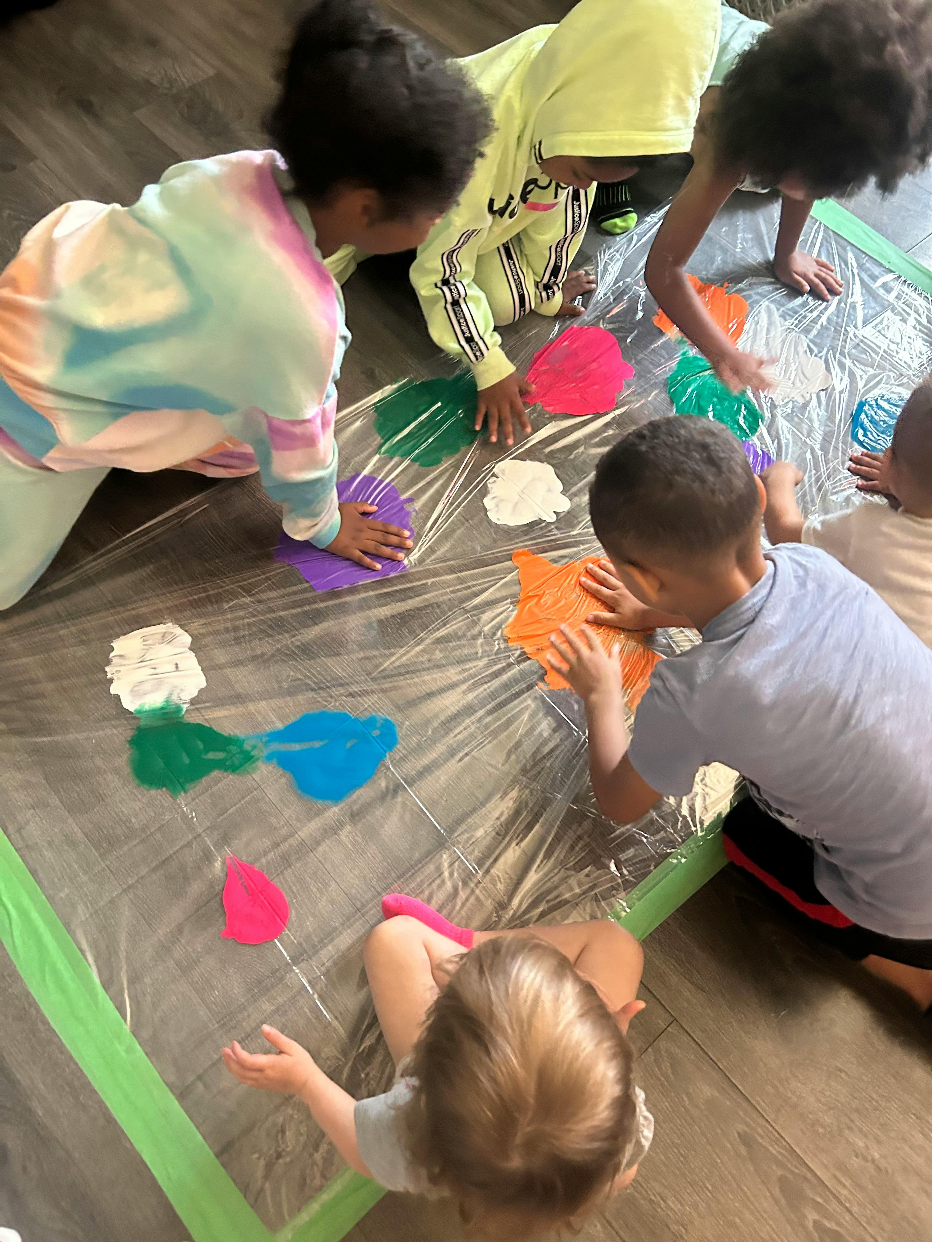 Children playing with paint on a plastic sheet