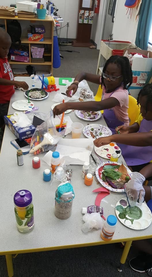 Children at a table doing an art activity with paint and craft supplies