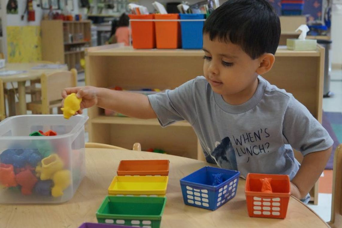 Child playing with colorful sorting toys in a classroom