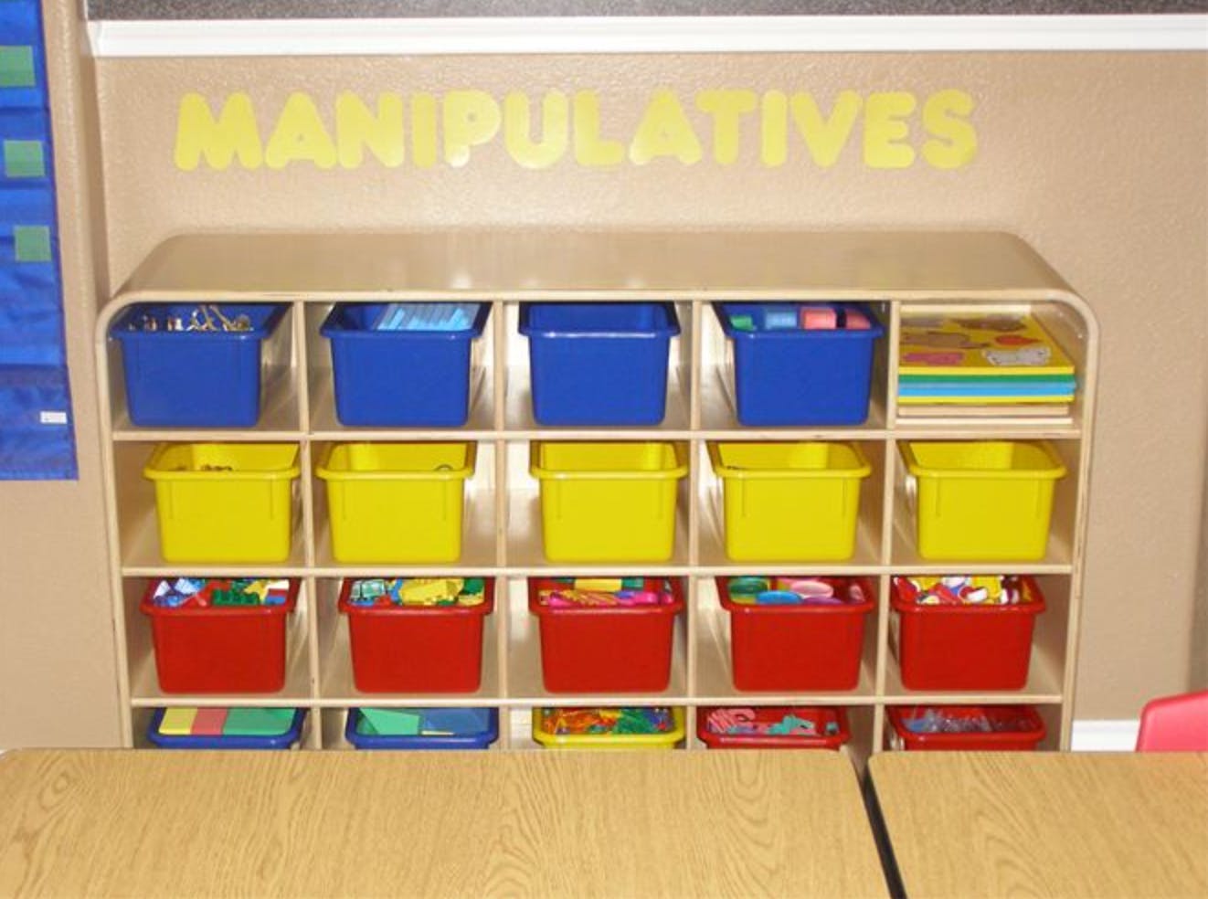 Shelving unit with colorful bins labeled "MANIPULATIVES"