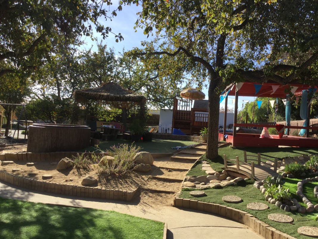 Outdoor play area with trees, a hot tub, and a red canopy