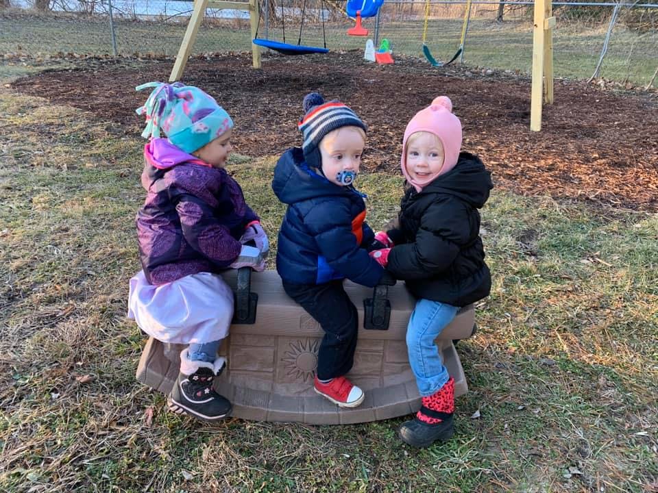 Three children sitting on a playground rocker