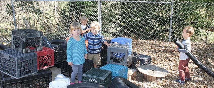 Children playing with crates and pipes outdoors