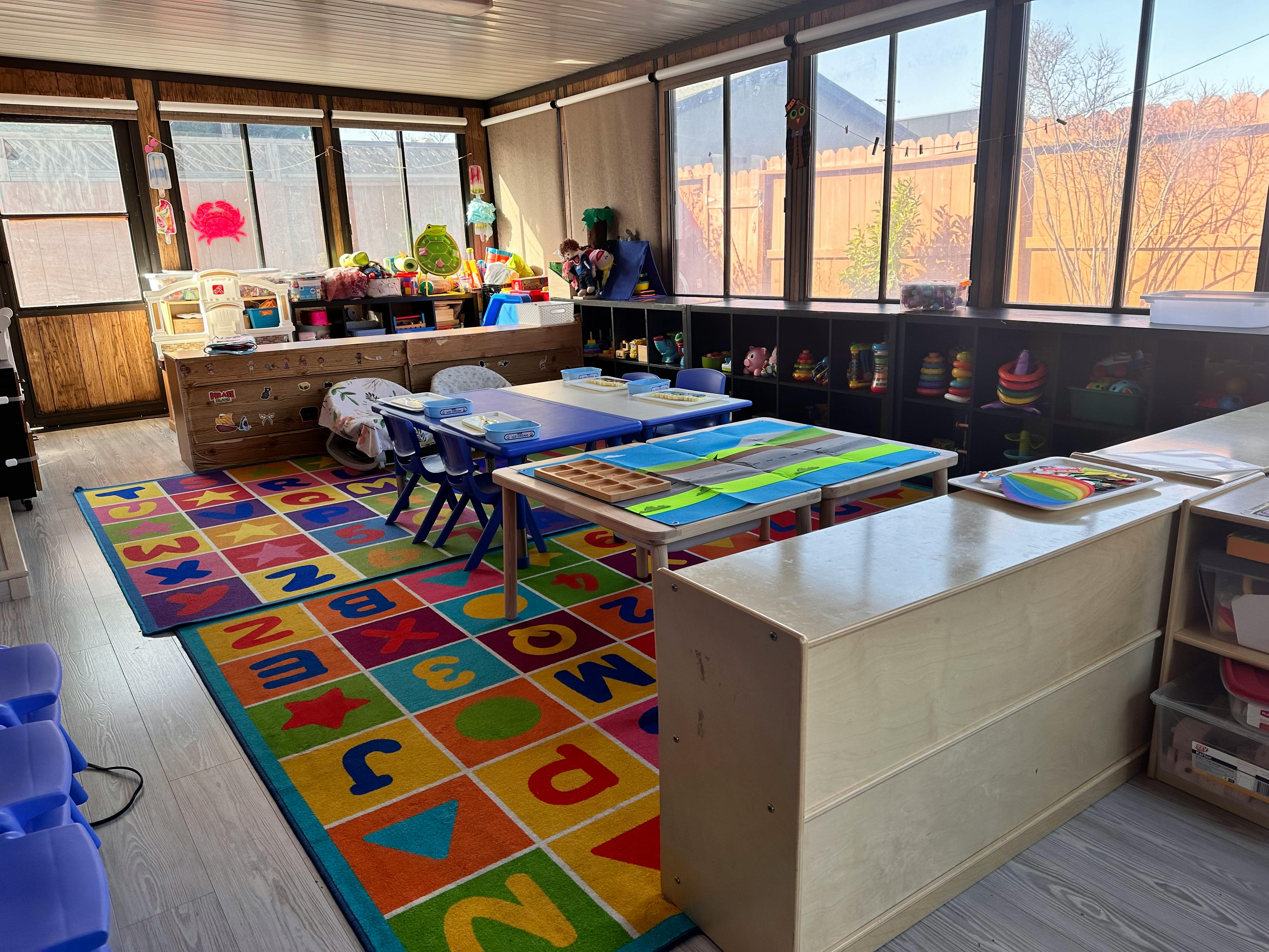 Classroom with colorful alphabet rug, tables, and chairs