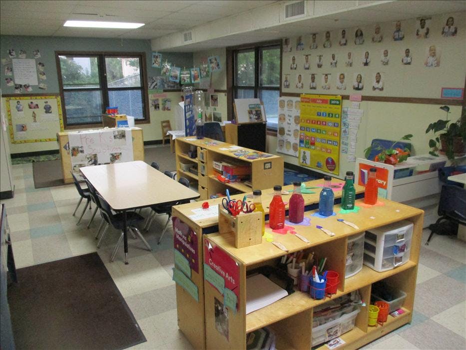 An empty classroom with tables, shelves, and art supplies