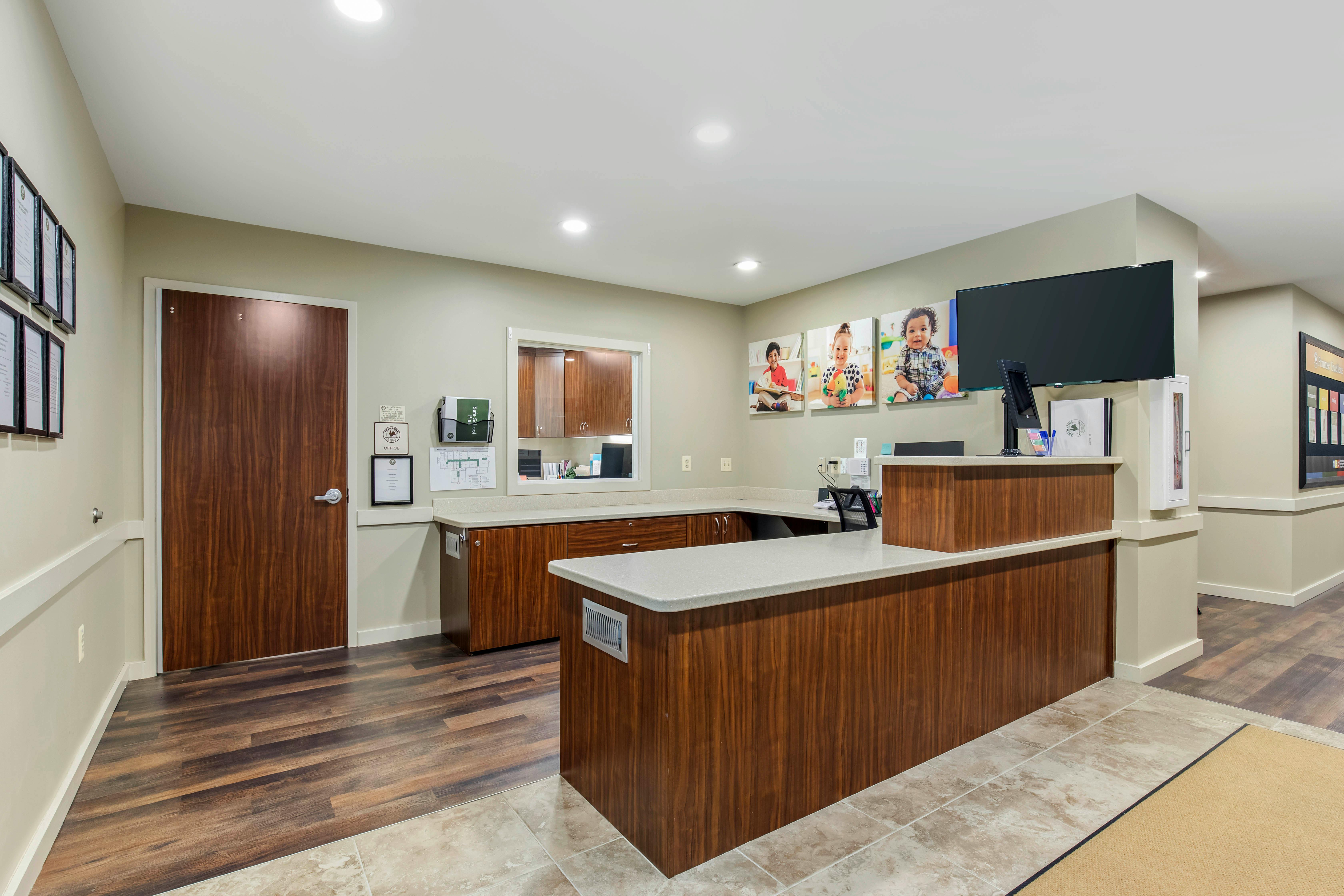Reception desk with wood paneling and light countertop, small window into back office
