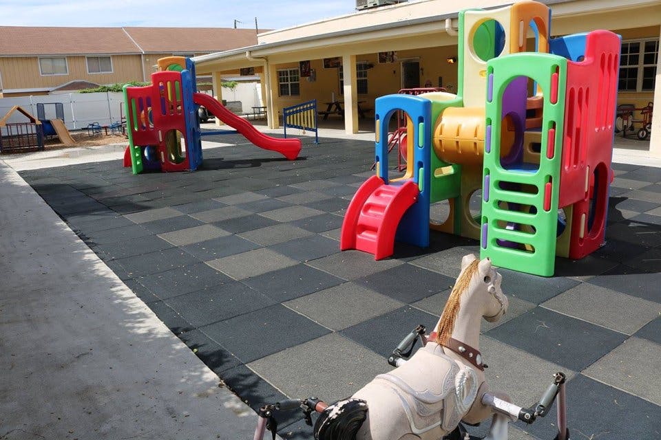 Outdoor playground with colorful slides and play structures on a checkered mat