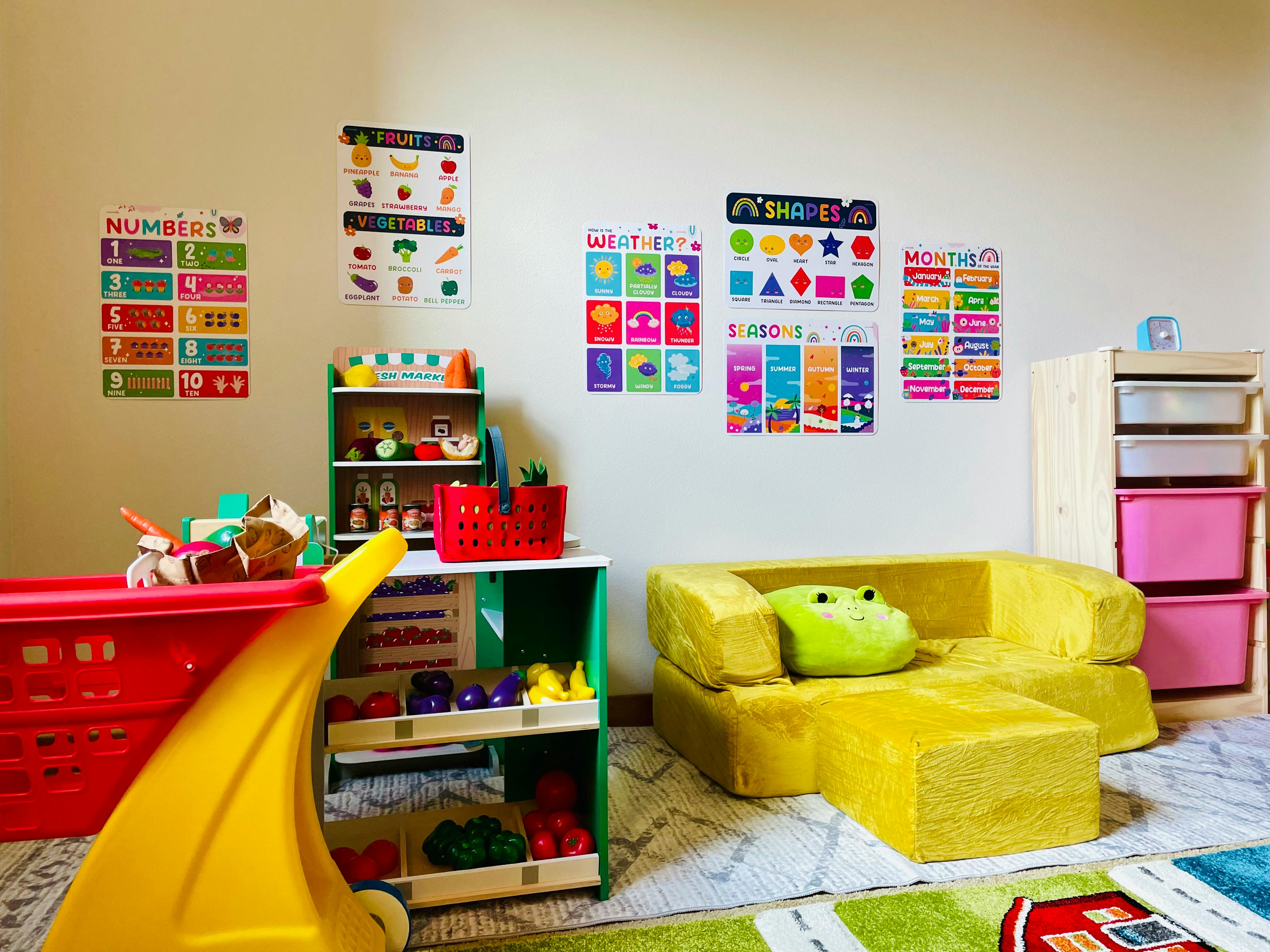 Playroom with educational posters, toy shelves, and a yellow children's sofa