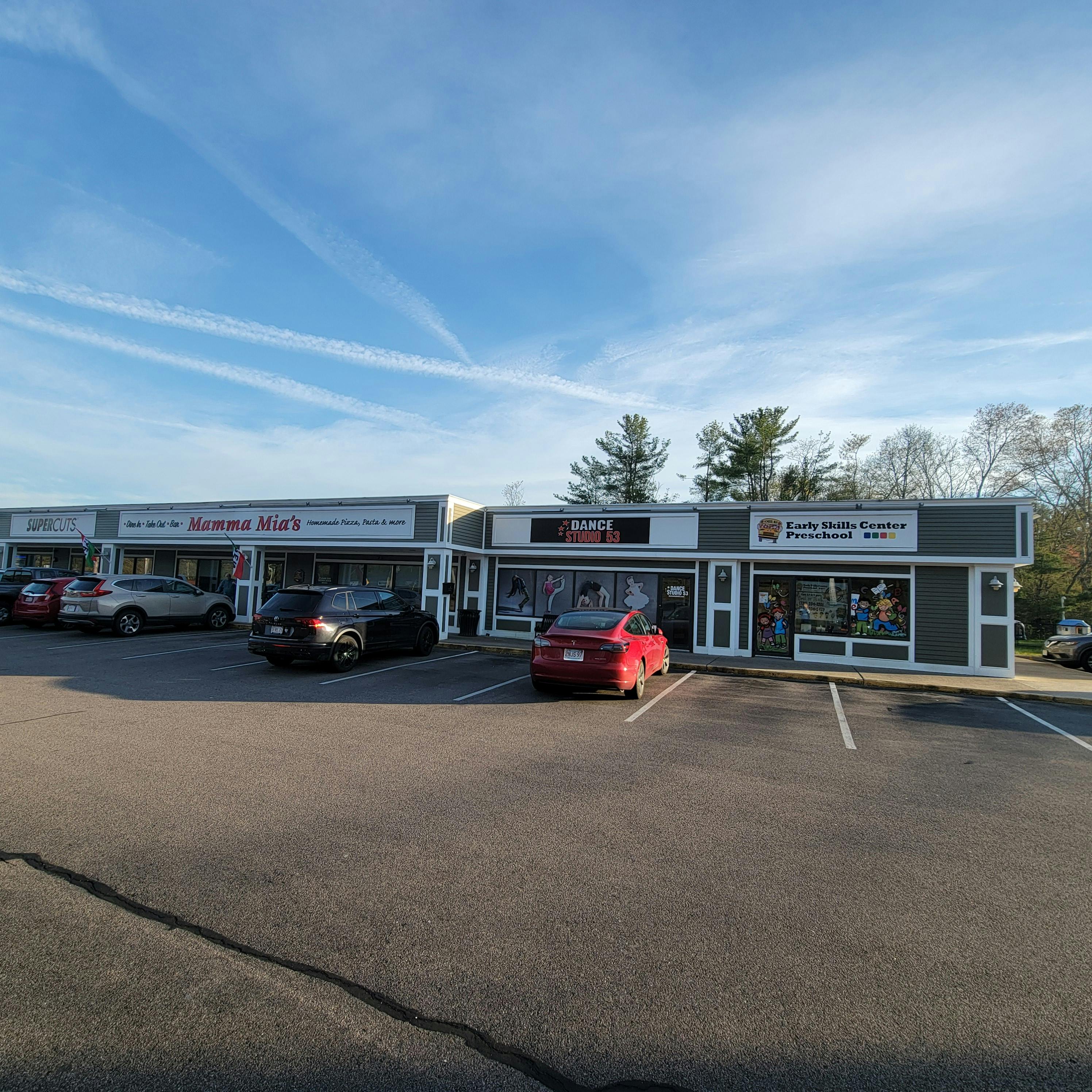 Strip mall with several storefronts and parked cars