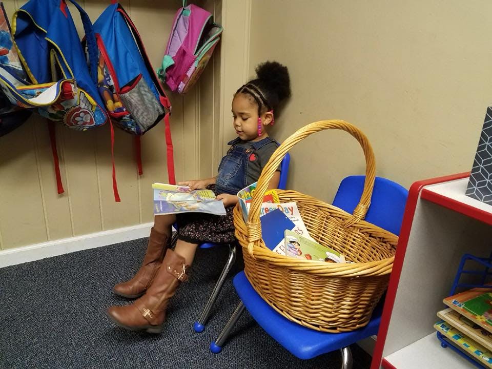 Child sitting on a chair reading a book