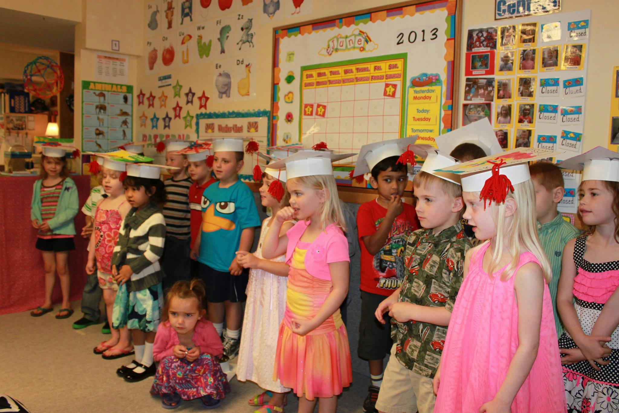 Children in graduation caps standing in a classroom