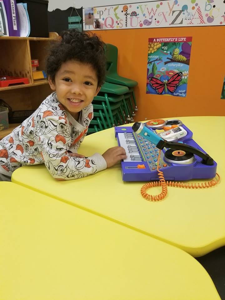 Child playing with a toy record player and microphone on a yellow table