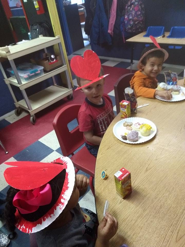 Children wearing paper hats at a table with plates of food