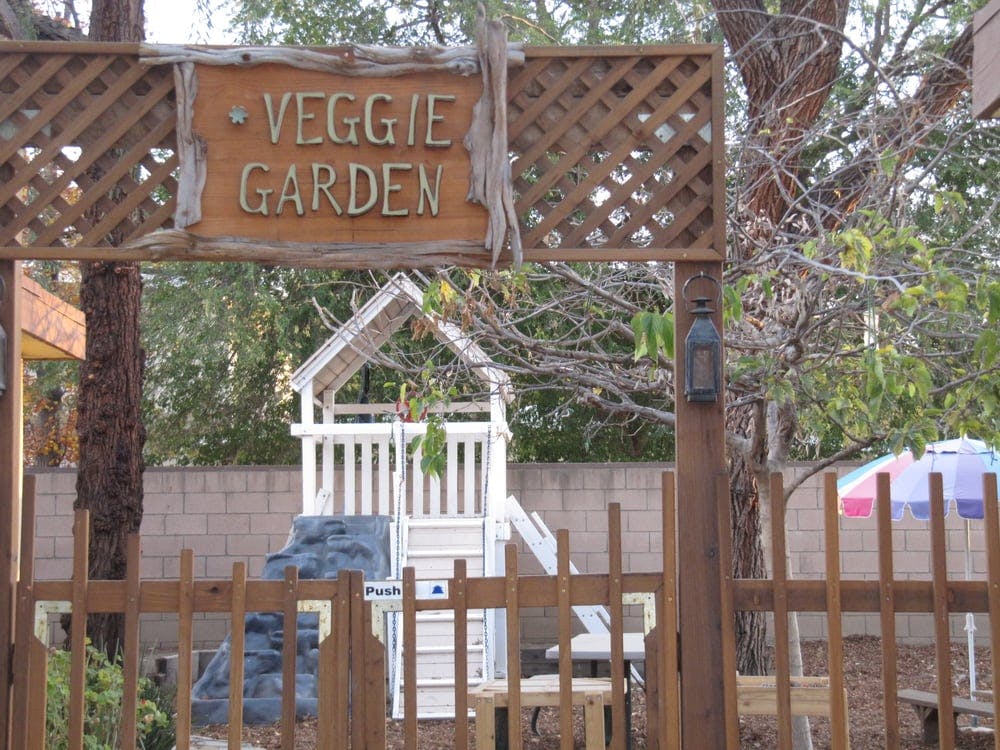 Wooden sign over a gate that reads "VEGGIE GARDEN"