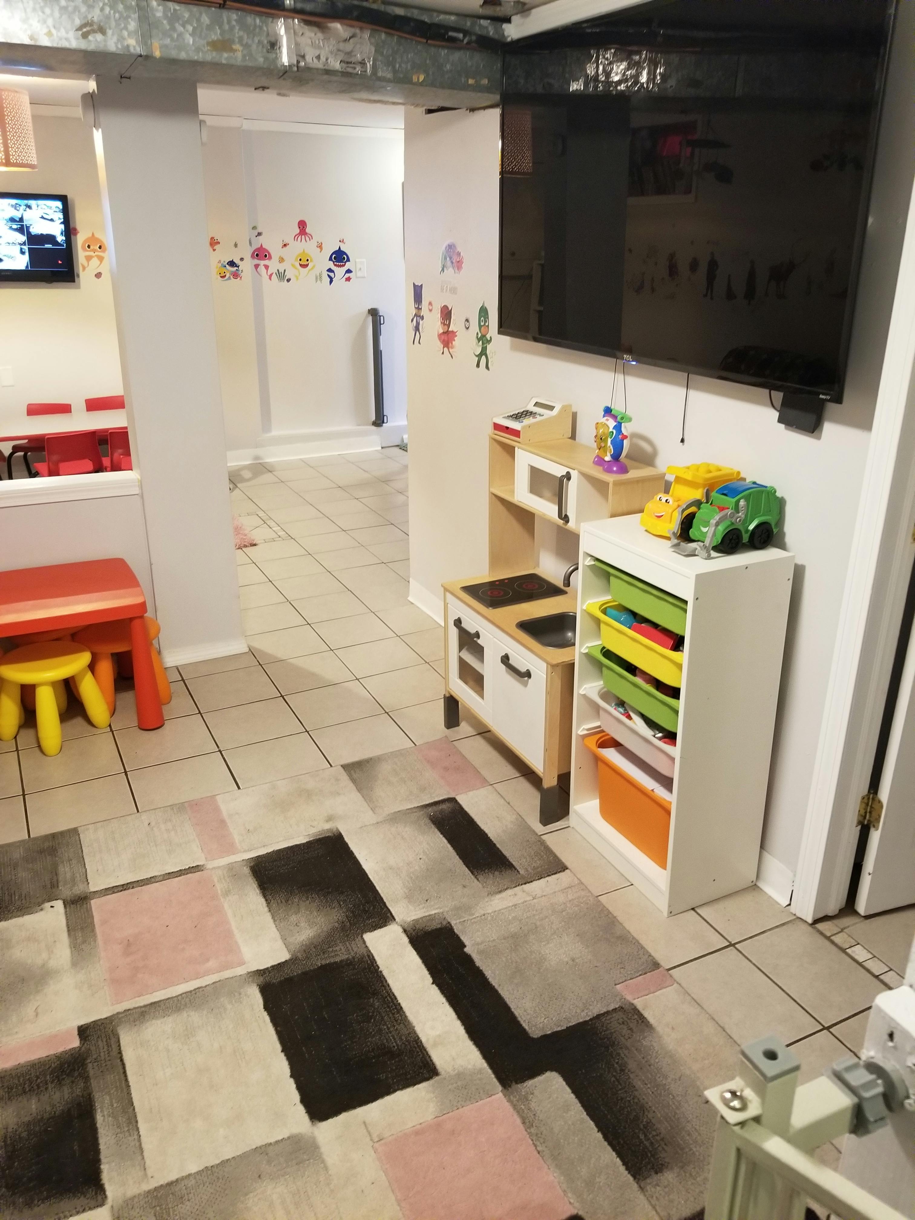 Children's play area with toy kitchen, storage unit, and small tables
