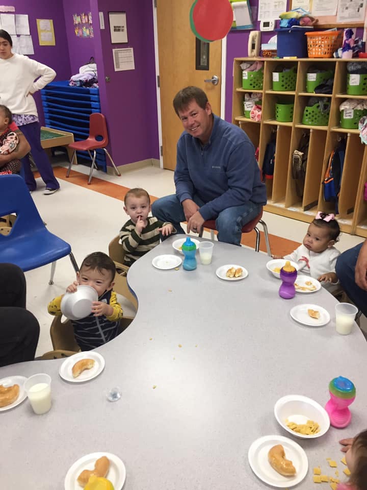 Adult and children sitting at a table with plates of food and drinks