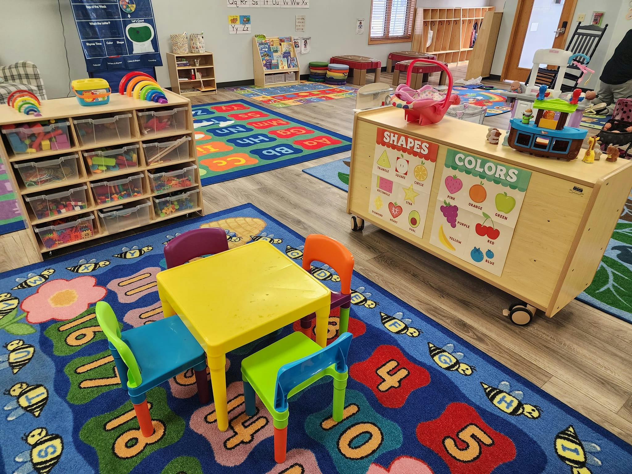 Children's classroom with colorful rugs, small tables, and storage shelves