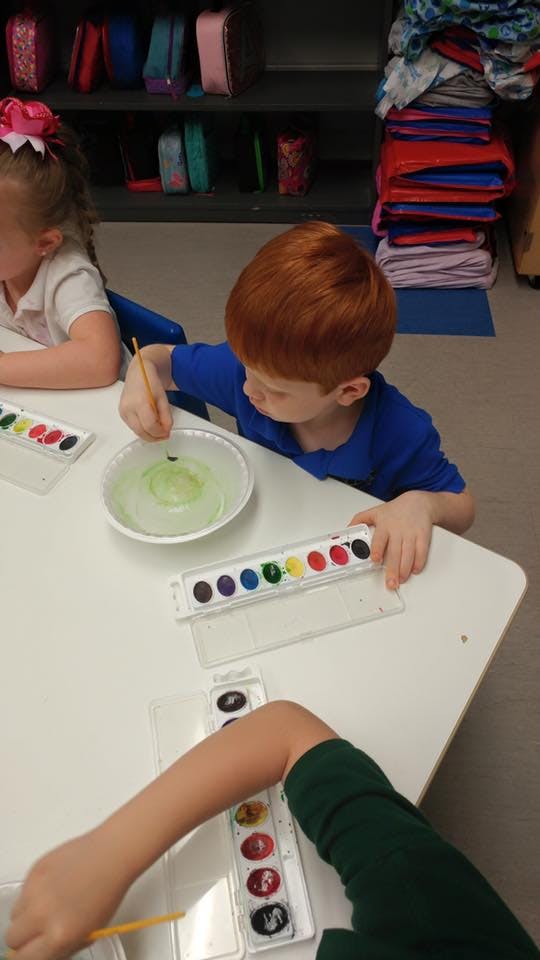 Child painting with watercolors at a table