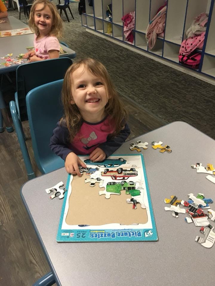 Child assembling a car puzzle at a table