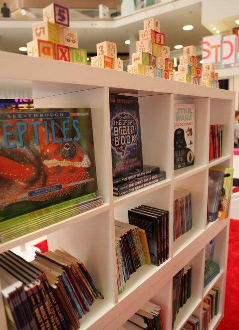 Books on a white bookshelf with alphabet blocks on top