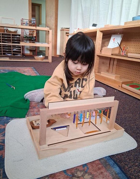 Child manipulating a bead frame in a classroom