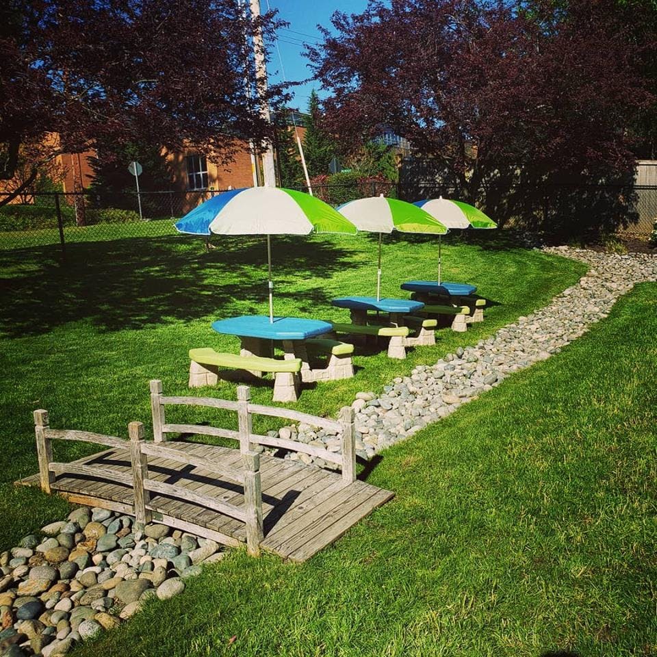 Wooden bridge over a dry creek bed with picnic tables and umbrellas in background