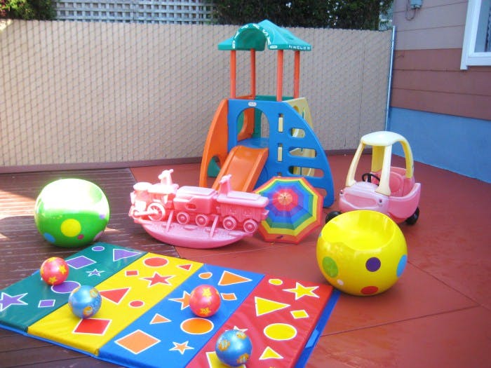 Children's outdoor play area with slide, ride-on toy, and balls