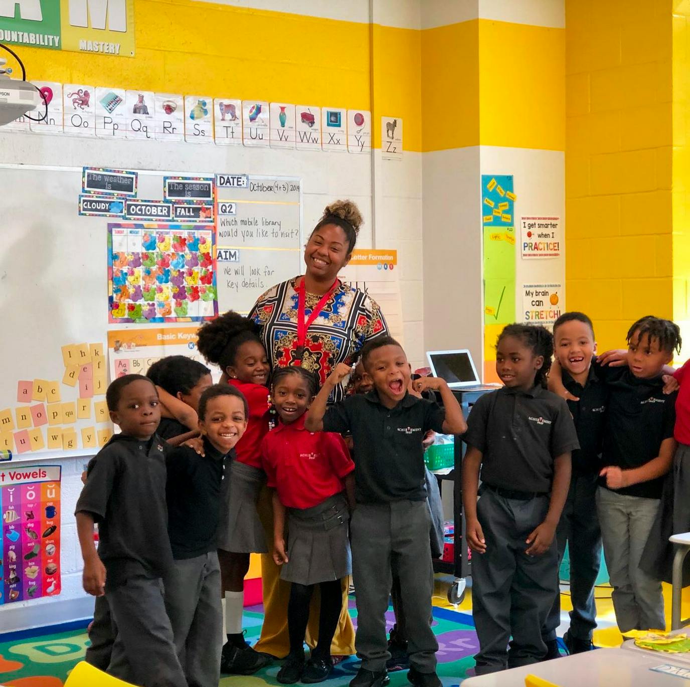 Adult and group of children posing in a classroom