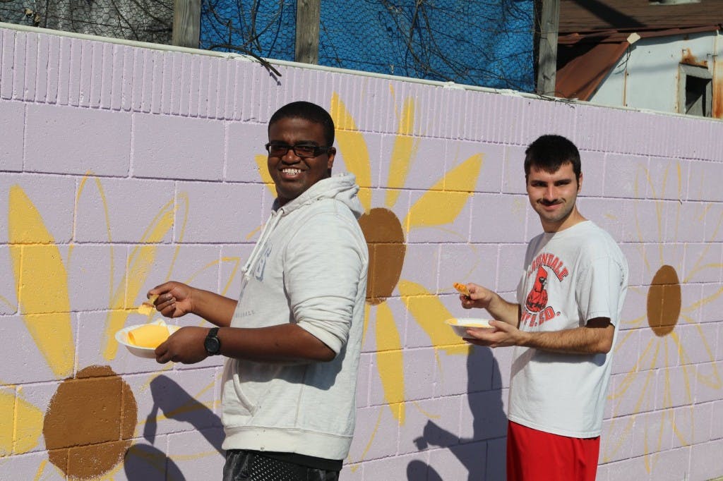 Two people painting a mural on a wall