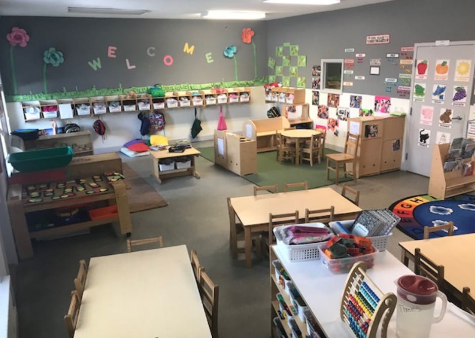 A classroom with small tables and chairs, and a "WELCOME" sign on the wall