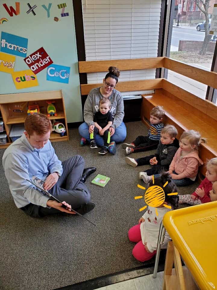 Adults and children sitting on the floor in a classroom