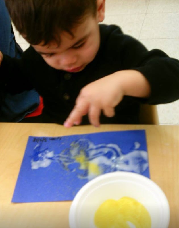 Child finger painting on blue paper
