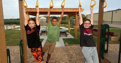Three children hanging from monkey bars on a playground