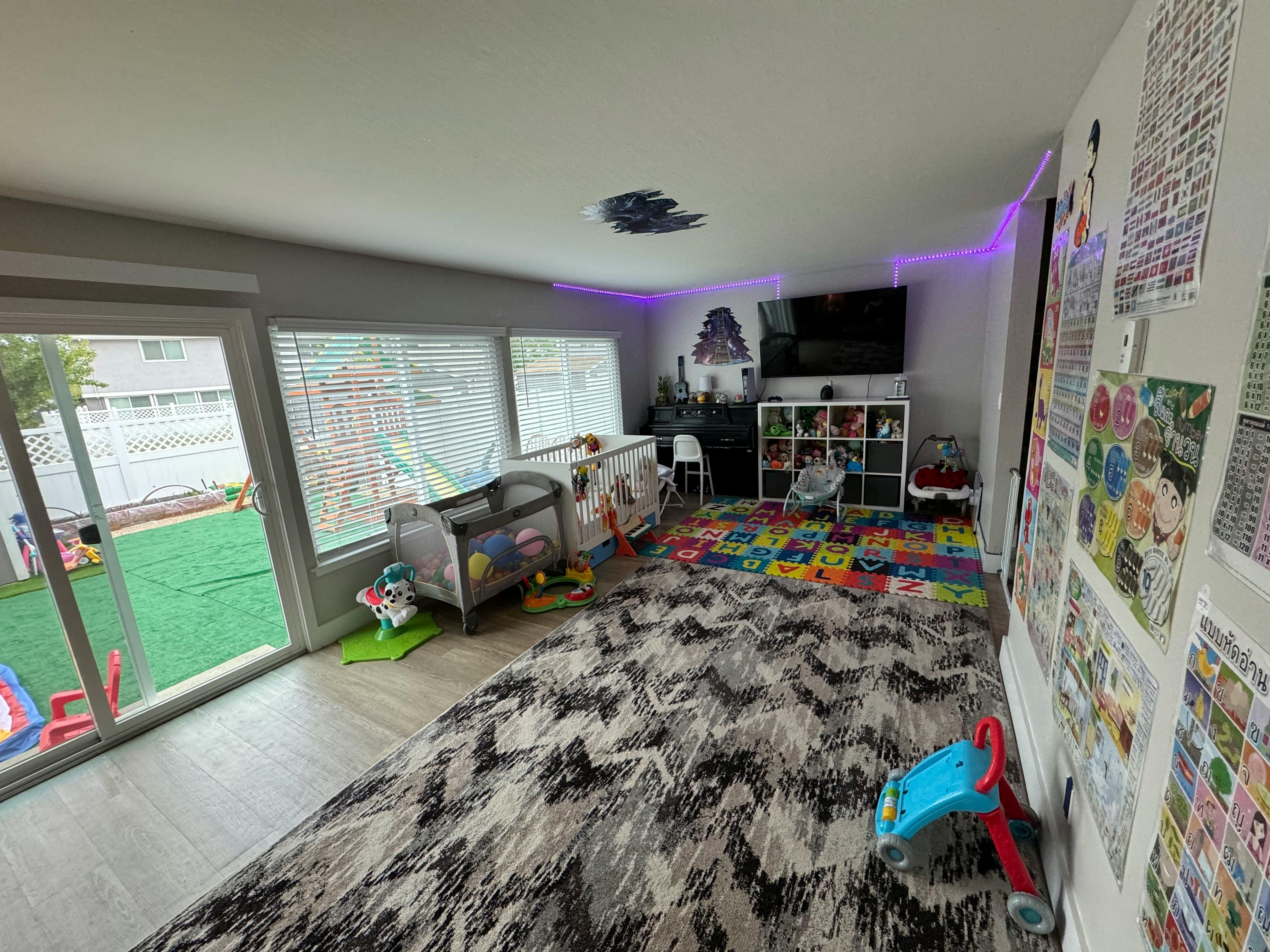 Playroom with crib, colorful floor mats, and sliding glass door to yard