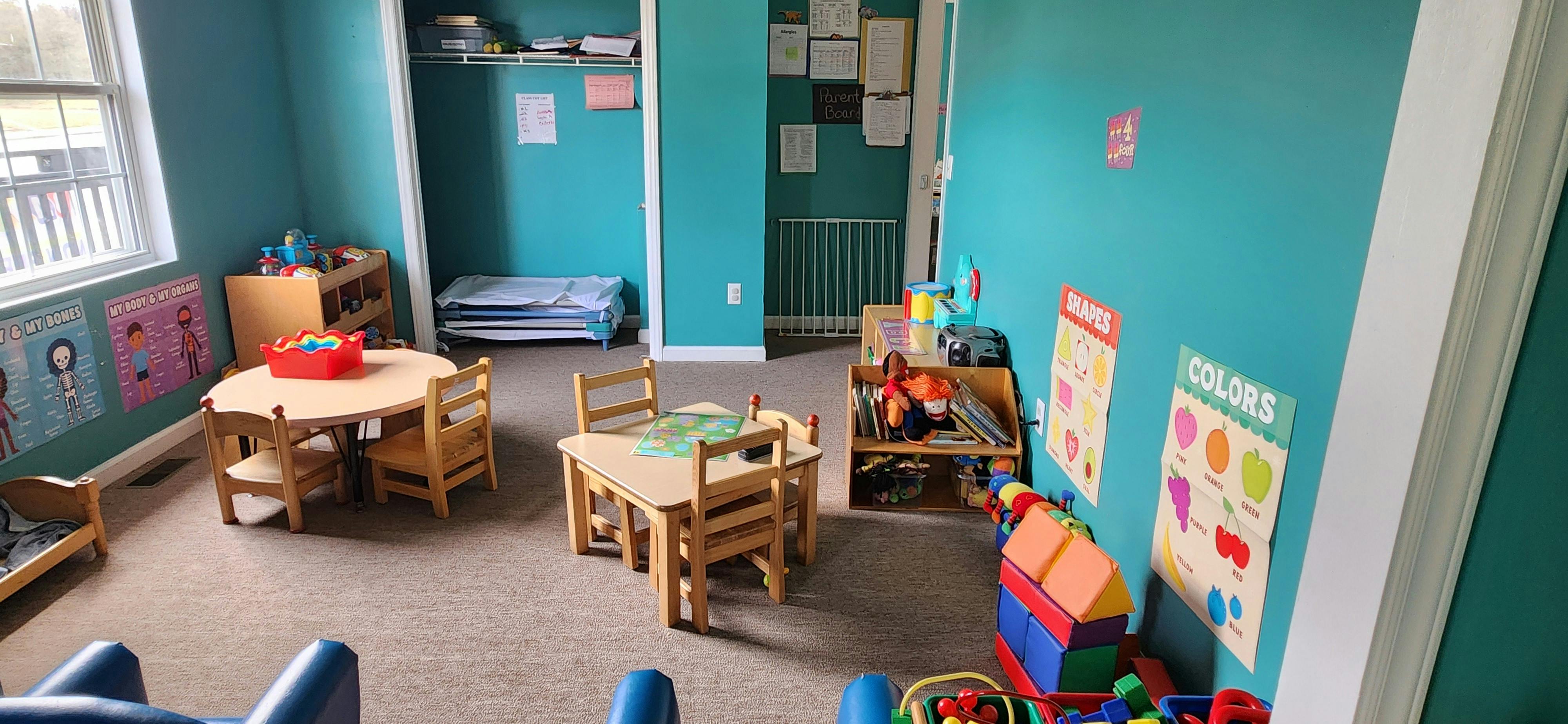 Classroom with small tables and chairs, posters on the wall