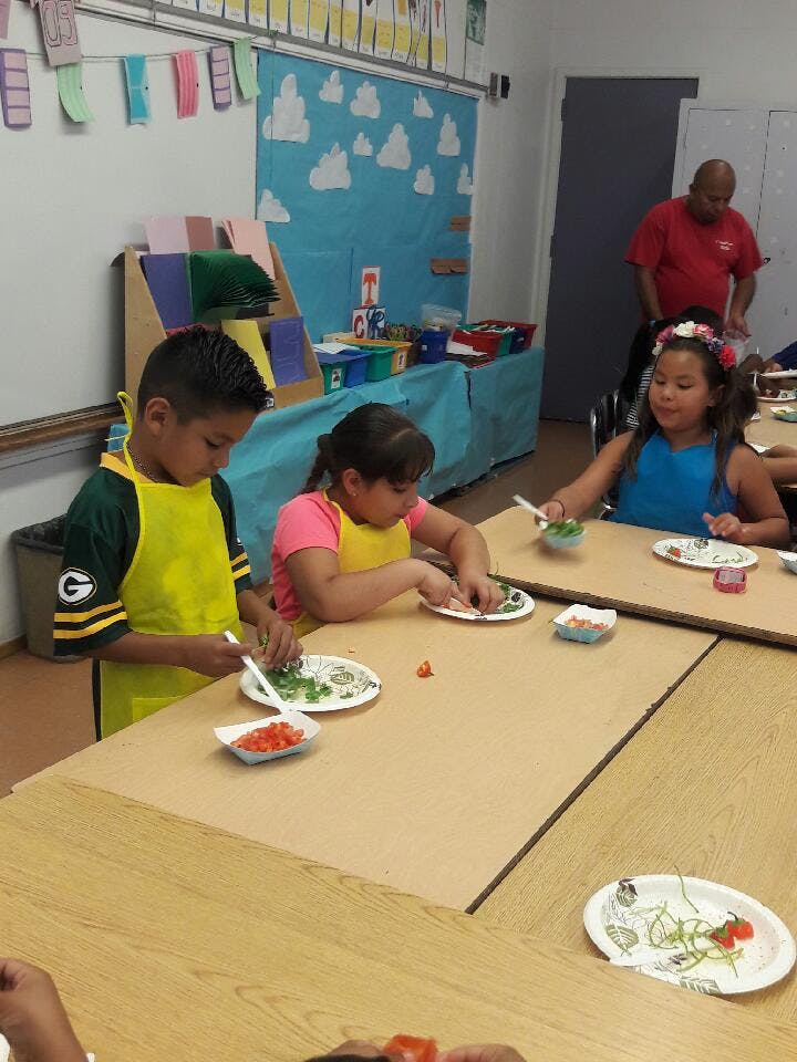 Children preparing food at a table in a classroom