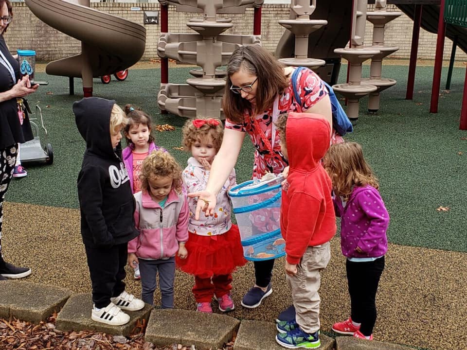 Adult showing something to a group of children on a playground