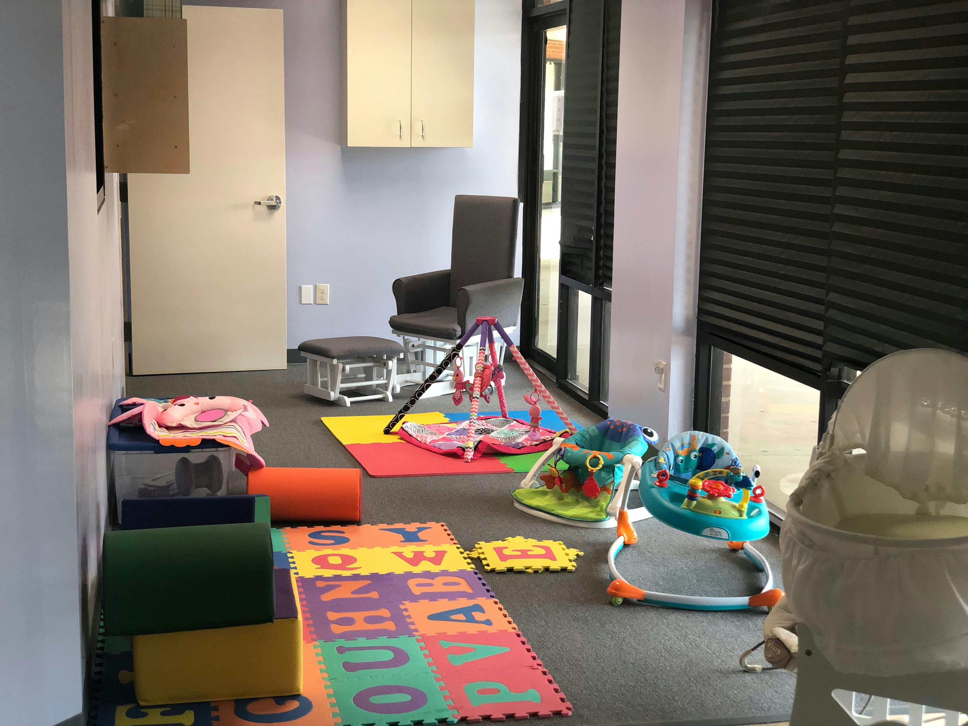 Playroom with colorful floor mats, baby activity centers, and soft play blocks
