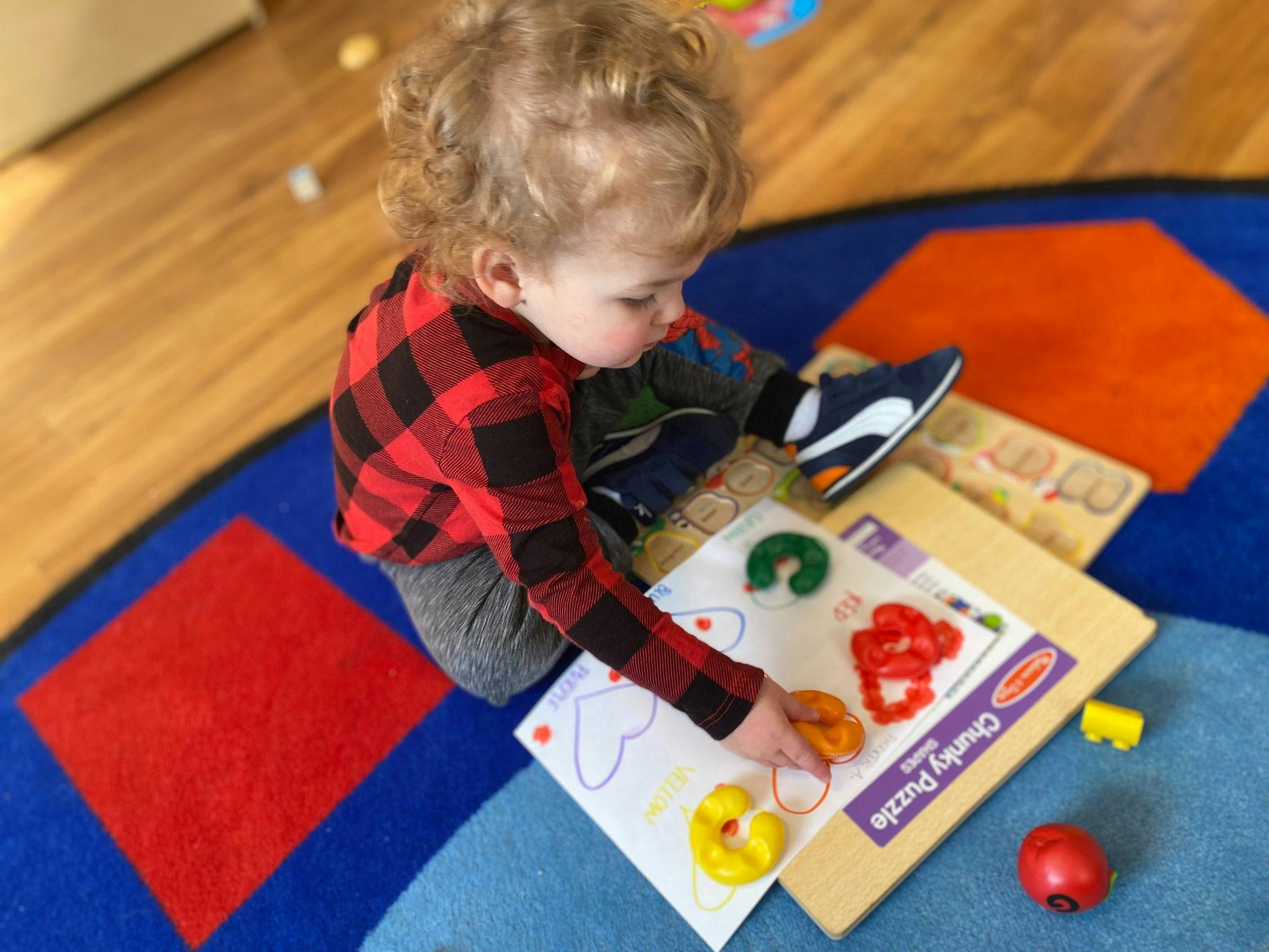 Child playing with a puzzle on a colorful rug