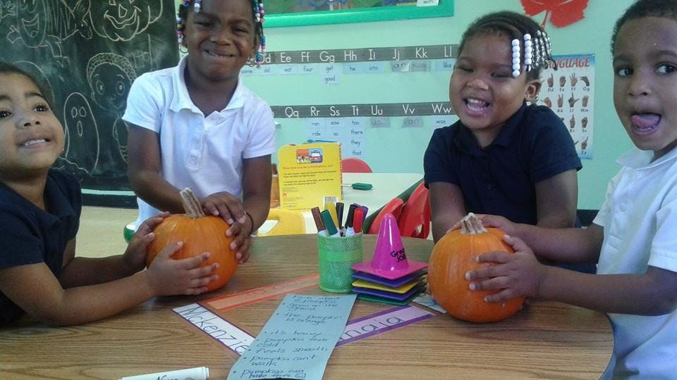 Four children at a table with pumpkins