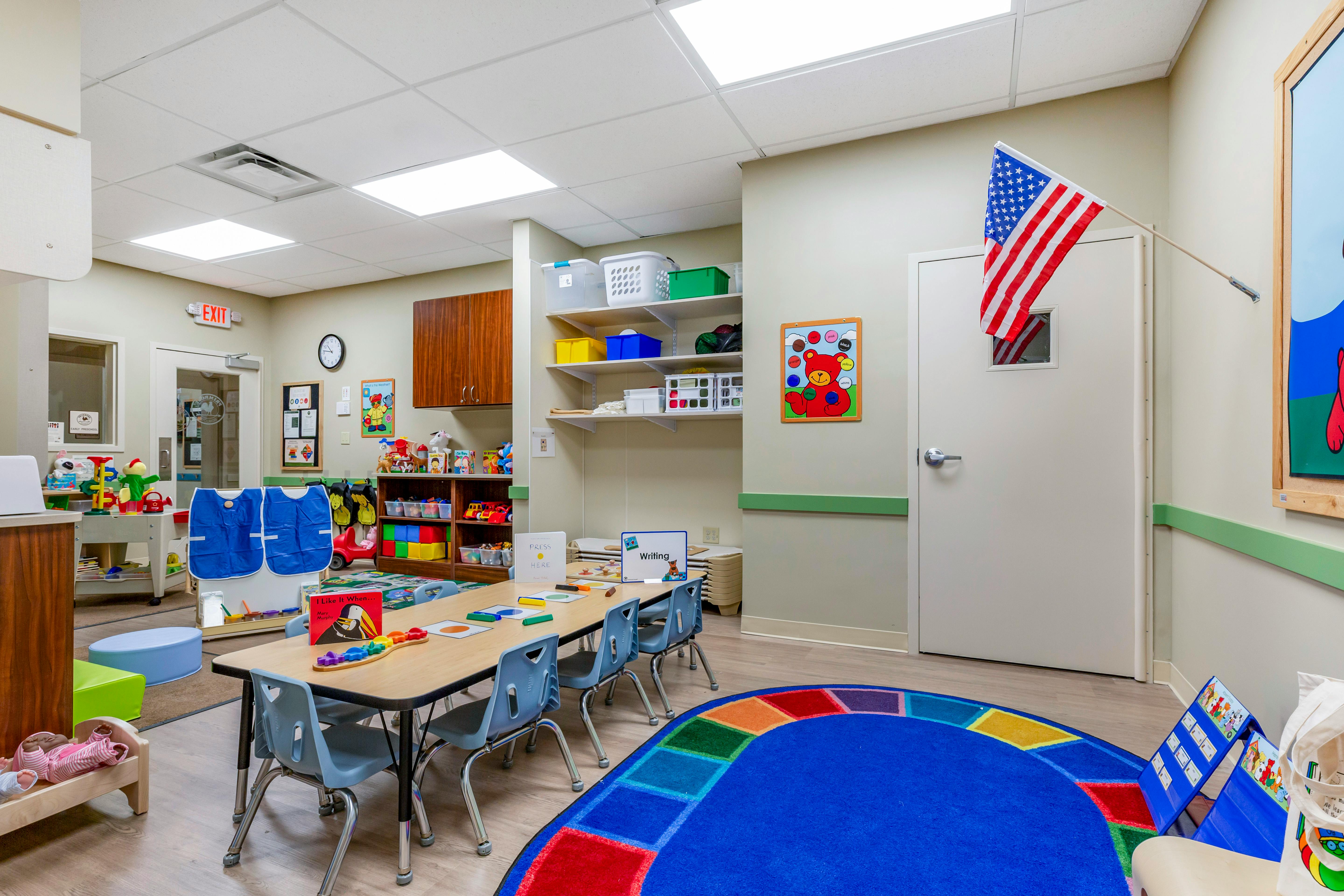 Classroom with child-sized tables and chairs, toys, and an American flag