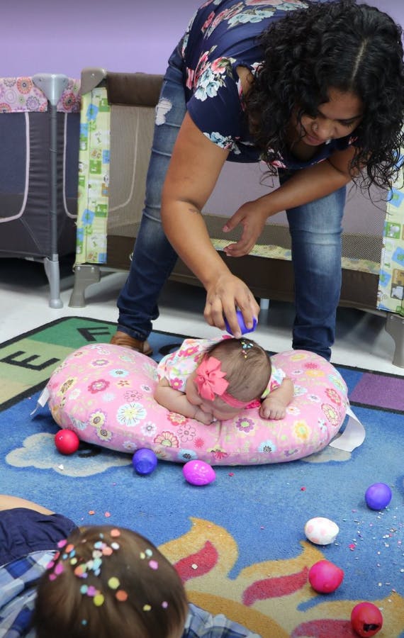 Person pouring confetti on a child lying on a pink pillow