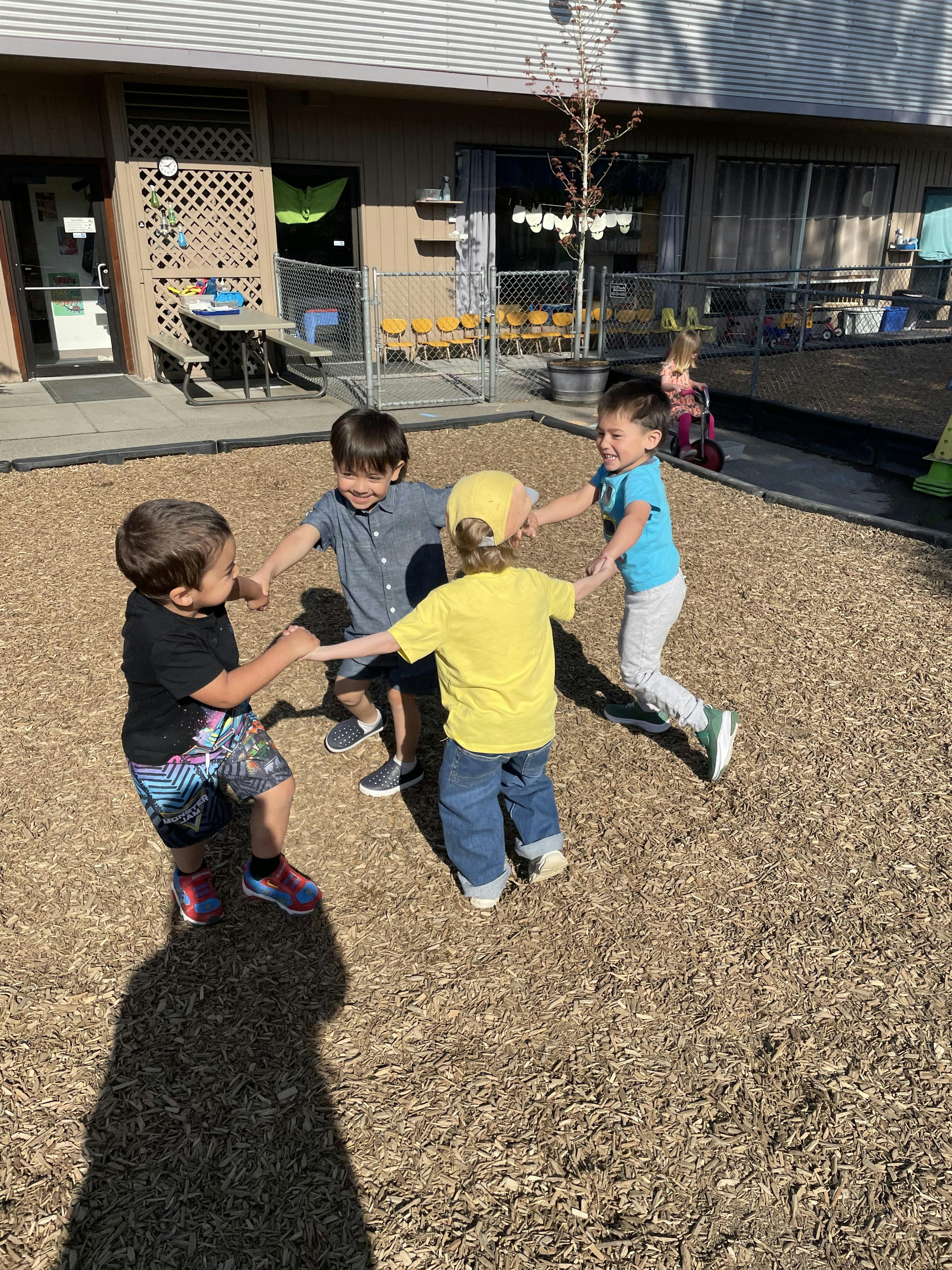 Four children holding hands in a circle on a playground