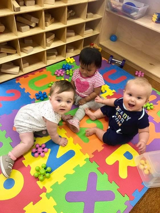 Three babies playing on a colorful alphabet mat