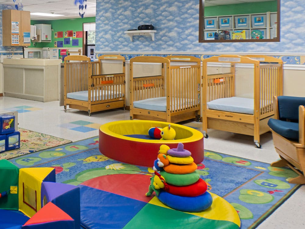 cribs and play area with soft colorful shapes in a childcare classroom